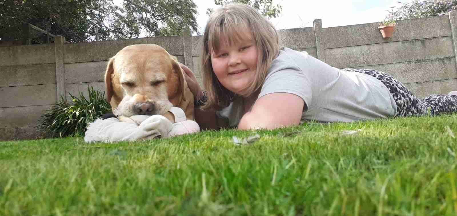 Jess lying on the grass with a dog
