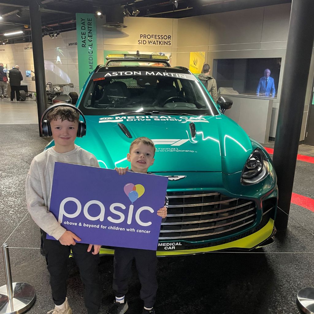 Children pose with Pasic sign in front of car